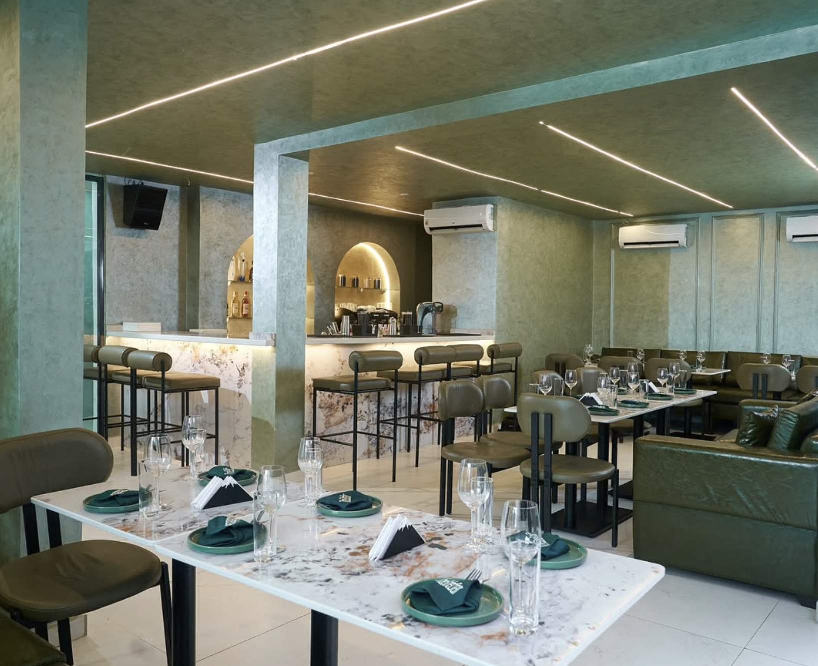 The renovated interior of Sidebar, Lekki — marble tables, olive seating and soft neon lighting